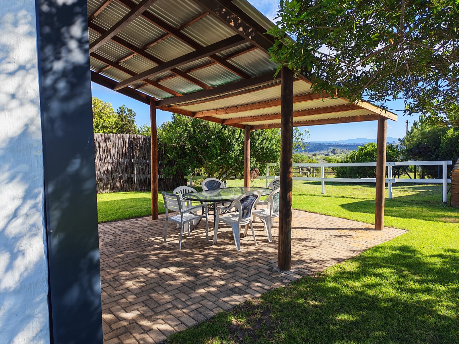 Shaded patio with table and chairs looking out over the lawn
